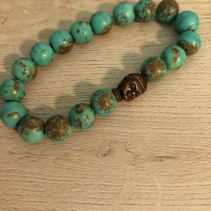 Turquoise bracelet with a Buddha head charm.